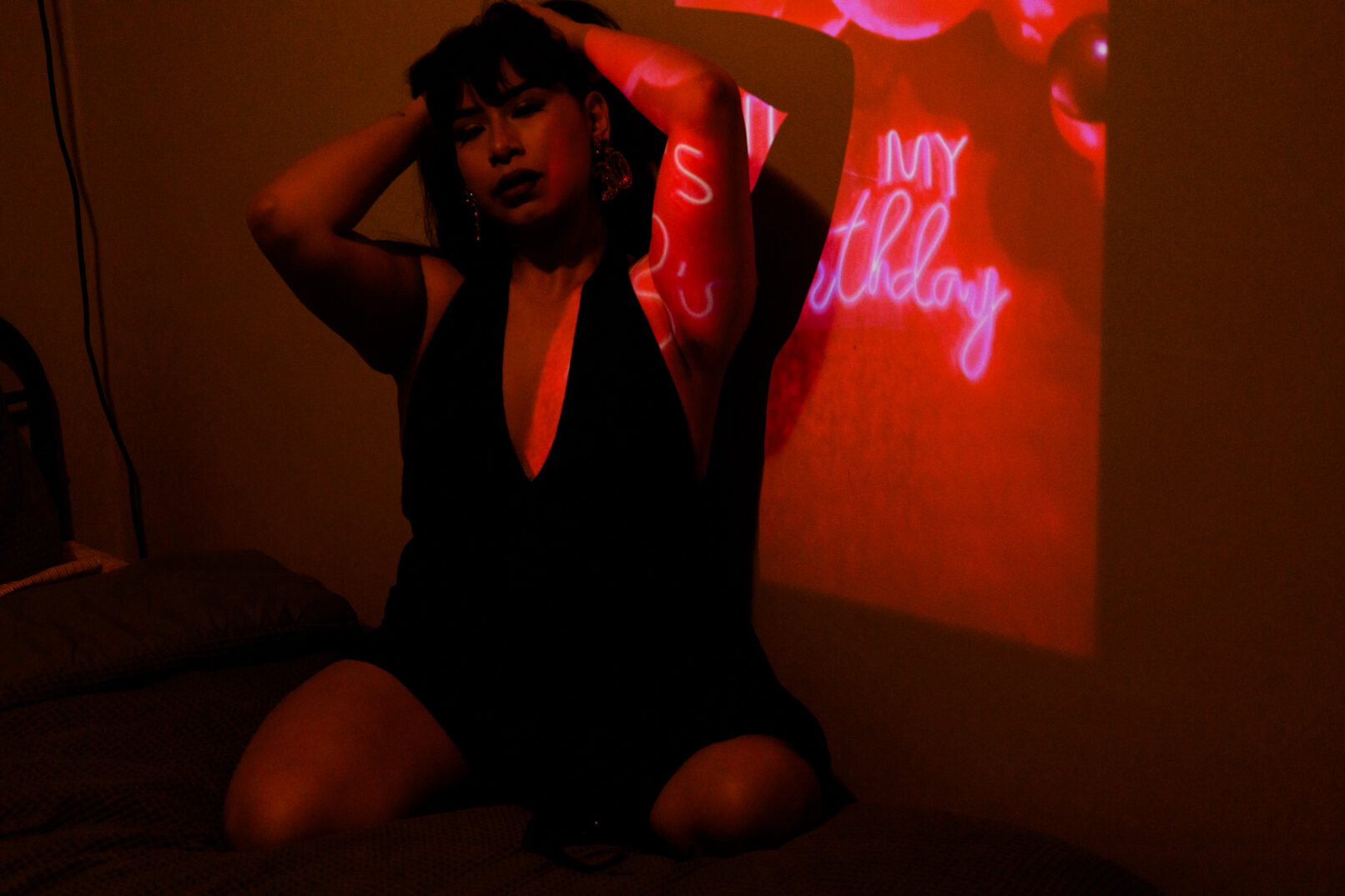 a woman on a bed, posing by a pink light