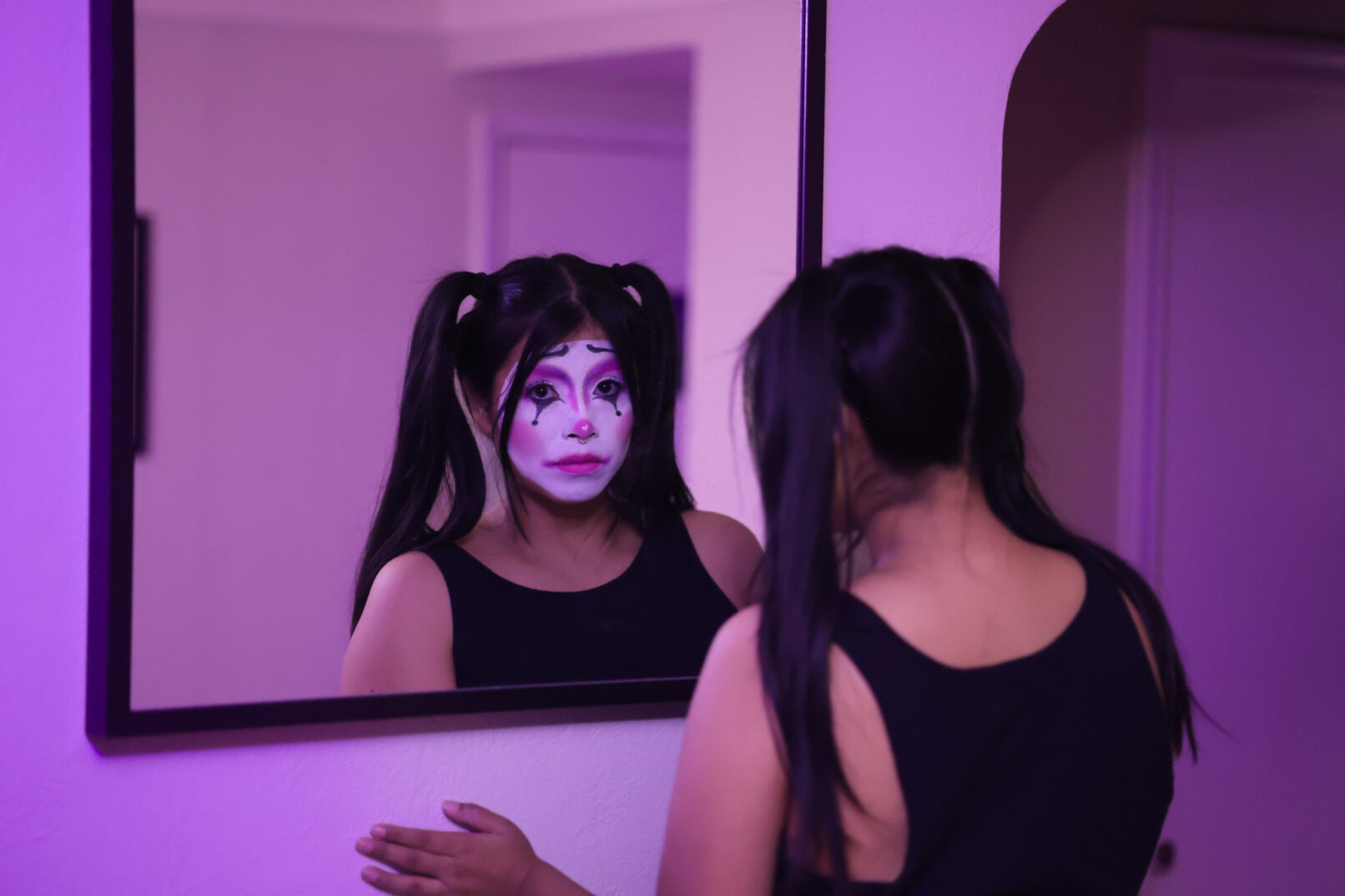 a woman with clown makeup looking in the mirror